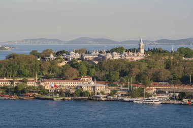 Topkapı Sarayı kompleksi. Etrafı orman parklarıyla çevrili. Boğaz 'ın diğer tarafından görülüyor. İstanbul 'daki ünlü tarihi mekan sıcak günbatımı tonlarıyla aydınlanıyor. İstanbul 20 Mayıs 2025
