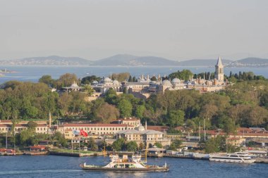 Topkapı Sarayı kompleksi. Etrafı orman parklarıyla çevrili. Boğaz 'ın diğer tarafından görülüyor. İstanbul 'daki ünlü tarihi mekan sıcak günbatımı tonlarıyla aydınlanıyor. İstanbul 20 Mayıs 2025
