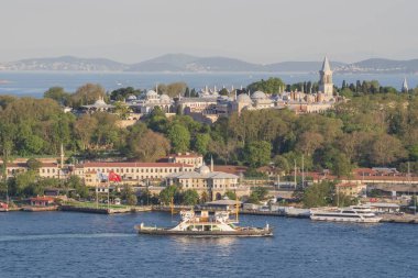 Topkapı Sarayı kompleksi. Etrafı orman parklarıyla çevrili. Boğaz 'ın diğer tarafından görülüyor. İstanbul 'daki ünlü tarihi mekan sıcak günbatımı tonlarıyla aydınlanıyor. İstanbul 20 Mayıs 2025