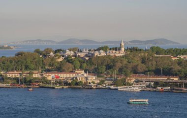 Topkapı Sarayı kompleksi. Etrafı orman parklarıyla çevrili. Boğaz 'ın diğer tarafından görülüyor. İstanbul 'daki ünlü tarihi mekan sıcak günbatımı tonlarıyla aydınlanıyor. İstanbul 20 Mayıs 2025