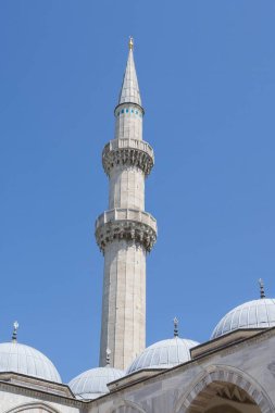 İstanbul 'daki bir Osmanlı camisinin mimari detayları. Mavi gökyüzünün altında kubbeler, kemerler ve uzun minareler var. Türkiye 'de tarihi İslami mimari ve kültür eseri.