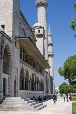 İstanbul 'daki bir Osmanlı camisinin mimari detayları. Mavi gökyüzünün altında kubbeler, kemerler ve uzun minareler var. Türkiye 'de tarihi İslami mimari ve kültür eseri.
