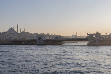 İstanbul semalarında gün batımı, Süleyman Camii, Boğaz ve liman boyundaki teknelerle birlikte yükseliyor. Türk ikonik şehri üzerinde tarihi Osmanlı mimarisi ve sakin akşam atmosferi.