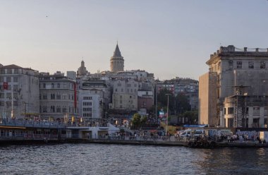 İstanbul 'daki Galata Kulesi ve liman kenti, açık bir gökyüzünün altında kayıklar, tarihi binalar ve canlı bir şehir atmosferi sergilenirken altın saatinde ele geçirildi. 20 Mayıs 2025