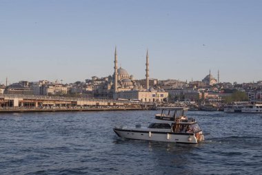 Günbatımında İstanbul 'un arka planında ufuk çizgisi olan Boğaz sularında süzülen özel yat, huzurlu bir akşamda deniz zarafeti, kıyı manzarası ve Türk deniz kültürü sergiliyor. 19 Mayıs 2025
