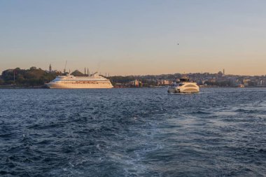 İstanbul limanında altın saatinde zarif yolcu gemileri, şehrin silueti ve liman manzaralı. Lüks seyahatin mükemmel tasviri, deniz turizmi ve manzaralı şehir ortamlarında tatil seyahatleri. Mayıs 19, 2025 