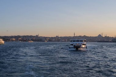 İstanbul, Türkiye 'deki İstanbul Boğazı' nda seyahat eden yolcu feribotları. Gemide bayraklı ve yolcuları olan deniz gemileri, şehrin silueti ve arka planda açık mavi su. 19 Mayıs 2025
