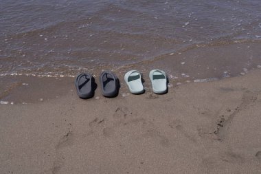 Atlantik Okyanusu 'ndaki plaj sandaletleri. Yaz rahatlığının rahatlatıcı bir sembolü, okyanusun huzurunu, sessizliğini ve farkındalığını çağrıştırıyor. Sakin bir kaçış için mükemmel bir atmosfer..