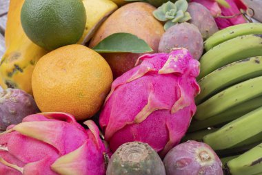 Sağlıklı yemek için çeşitli egzotik meyveler. Papaya, ejderha meyvesi, mango, muz, dikenli armut, limon ve portakal. Organik tropikal gıda, temiz beslenme ve vegan beslenme geçmişi.