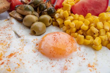 Yumurta, mısır, zeytin, midye ve tabakta tam tahıllı tost ile servis edilen taze domatesli sağlıklı bir kahvaltı. Besleyici protein öğünleri, dengeli diyet yemekleri, Akdeniz kahvaltısı..