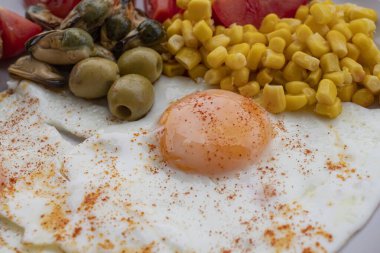 Yumurta, mısır, zeytin, midye ve tabakta tam tahıllı tost ile servis edilen taze domatesli sağlıklı bir kahvaltı. Besleyici protein öğünleri, dengeli diyet yemekleri, Akdeniz kahvaltısı..