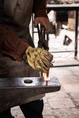 Demirci - bir çift maşayla erimiş metali elle döven demirci