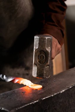 Demirci - demirci elle erimiş metali çekiçle dövüyor.