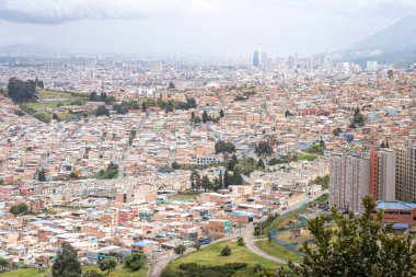 Bogota 'nın panoramik hava manzarası. Düşük katlı ve yüksek katlı binalar, yeşil alanlar ve bulutlu bir gökyüzünün altındaki uzak bir gökyüzü.