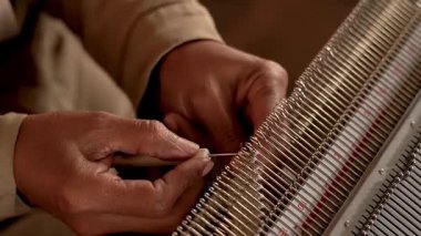 Bir atölyede el örgüsü makinesi kullanan zanaatkar ellerin yakın çekimi..