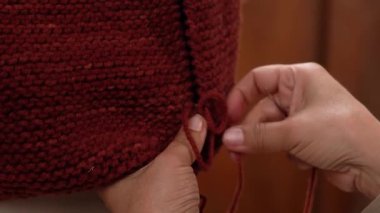 İğne ve iplik kullanarak kahverengi yün kumaşı diken ellerin yakın çekimi..