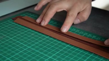 Zanaatkâr ellerin yakın plan çekimleri deri mücevher kutusunu yeşil hasırda hassas aletlerle şekillendiriyor..