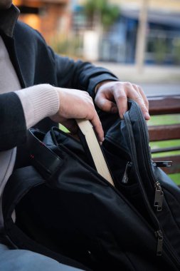 Zarif bir iş adamının bavulundan kitap çıkarırken çekilmiş fotoğrafı. Dışarıda, parkta.