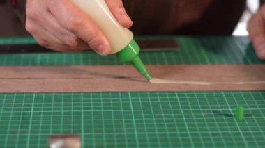 Sıkıştırılmış şişeden yapıştırıcı sürerek deri ya da başka bir el işi malzemesine yakın plan..