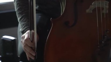 Bir insanın yayı tutarken ve bas gitar çalarken yakın plan çekimleri. Odak noktamız yayın hareketi ve enstrümanın bedeni..