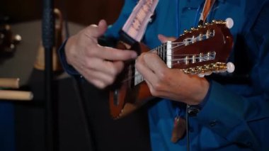 Charango çalan birinin yakın çekimi, Andean telli küçük bir enstrüman. Müzisyenin ellerine ve enstrümanına odaklanarak, karmaşık parmak izlerini ve Charango 'nun eşsiz sesini vurguluyor.. 