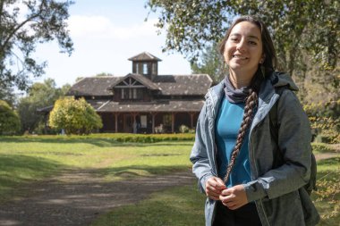 Frutillar, Şili 'deki Alman Koloni Müzesi' nde gülümseyen genç bir İspanyol kaşif. Alman evinin yakınındaki bir turist.