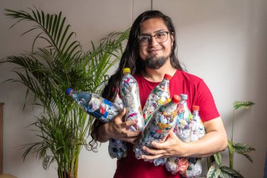Evde plastiği geri dönüşüm için kullanan bir adam. Paketlerle dolu plastik şişeler. 