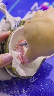 Diş teknisyeninin diş eti renginde bir protezi kalıbın içinde rafine etmek için döner bir alet kullandığı yakın plan..