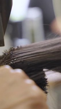 Kuaförde düz saç stili yapmak için yuvarlak fırçayla kullanılan saç kurutma makinesinin detaylı görüntüsü.