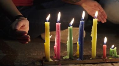 Parlak renkli mumlar kaldırımda bir sırada yanar ve gece ılık ve neşeli bir parıltı yaratır..