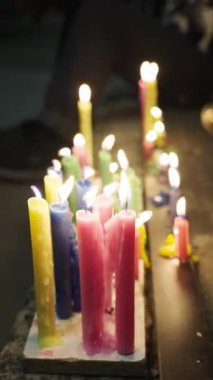 Yerde yanan renkli bir mum kümesi, gece vakti toplanan sıcak bir ışık saçıyor..