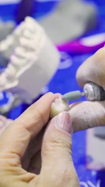 Eller kil ya da taşı şekillendirmek için döner bir araçla çalışıyor, ustalığı vurguluyor.