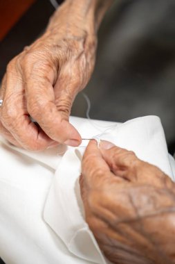 Yaşlı terzi. Eller dikiş, ölçme, kesme ve elle dikme ile çalışıyor. Yaşlı kadın terzi.