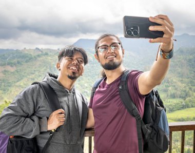 Dağlık bir arazide selfie çeken iki Latin adam. İki genç adam dağda otostopçu arkadaşlar selfie çekiyorlar.