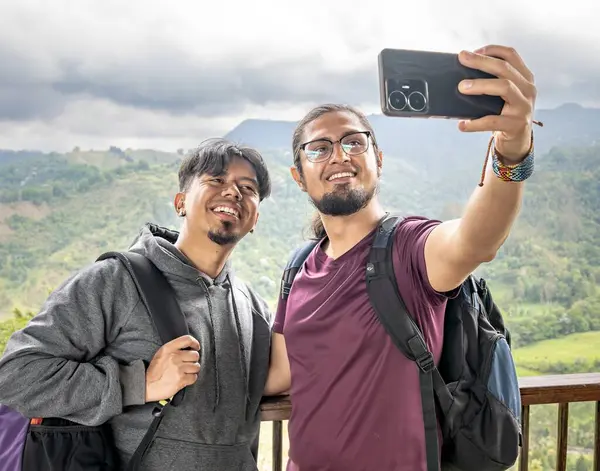 Dağlık bir arazide selfie çeken iki Latin adam. İki genç adam dağda otostopçu arkadaşlar selfie çekiyorlar.