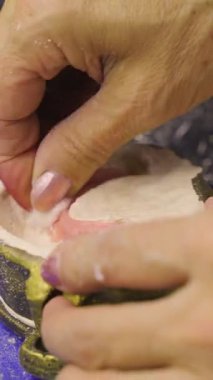 Diş kalıbını manipüle eden ellerin yakın çekimi, muhtemelen bir laboratuarda takma dişleri şekillendirirken veya şekillendirirken..