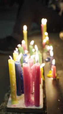 Taştan bir yüzeyde geceleri yanan renkli mumlar muhtemelen kültürel bir kutlama sırasında sıcak ve huzurlu bir ortam yaratıyor. Kolombiya Mumlar Günü.