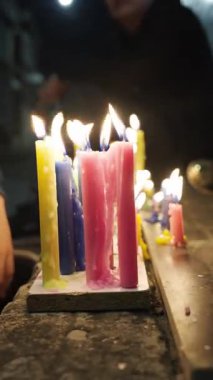 Renkli dua mumları (sarı, mavi, pembe) karanlık ve ruhani bir ortamda yanar. Alevler parlak ve balmumu yanlardan erir. Umut kavramı. Da de las velitas Kolombiya.