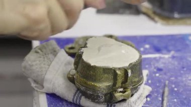 Diş teknisyeni spatula kullanarak beyaz alçıyı diş macununun içine karıştırıp döküyor. Laboratuvarda takma dişler için küf oluşturma süreci.