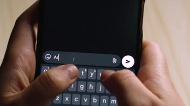 Bir sohbet uygulamasında Arrivederci 'yi yazarken akıllı telefonu tutan ellerin yakın çekimi, İtalyanca' da kibarca veda etmek.