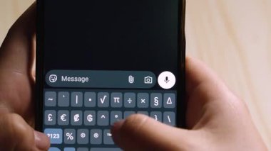 Dijital bir mesajda mutluluğu ya da arkadaşlığı ifade eden, telefonda gülen surat ifadelerini yazan ellerin yakın çekimi.