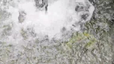 Türbülanslı bir su akışının çok sayıda kabarcık, köpük ve köpük içeren soyut görüntüsü güçlü bir akıntı veya şelale olduğunu gösteriyor..