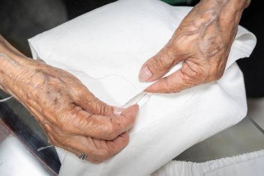 Yaşlı terzi. Eller dikiş, ölçme, kesme ve elle dikme ile çalışıyor. Yaşlı kadın terzi.