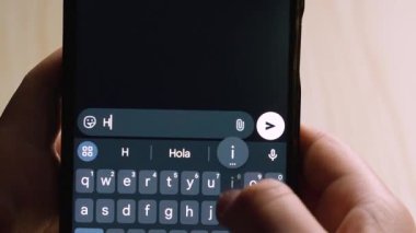 Koyu temalı sohbet arayüzüne neşeli bir karşılama mesajı yazarken akıllı telefonu tutan ellerin yakın çekimi.