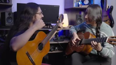 İki müzisyen, sıcak ve yaratıcı bir ev stüdyosunda klasik gitar çalarken keyifli bir anı paylaşıyor..