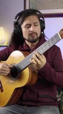 Etkileyici bir müzisyen klasik gitar çalar ve kapalı bir stüdyoda duygusal bir şekilde şarkı söyler..