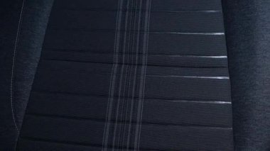 Paralel dikişli, ince parıltılı, araba koltuğu kumaşlı koyu renkli bir tekstil yüzeyi..