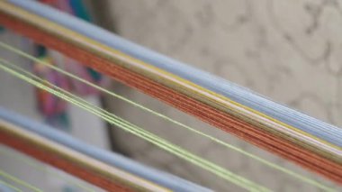 Geleneksel dokuma ve tekstil yaratımı için hazır, dokuma tezgahına gerilmiş düzgünce dizilmiş renkli ipliklerin yakın çekimi.
