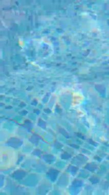 Açık mavi yüzme havuzu suyuna yakın çekim güneş ışığı döşeme üzerinde dalgalanmalar ve yansımalar yaratır..