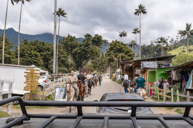 Kolombiya 'nın Cocora Vadisi' ndeki kırsal köyde at süren turistler. Salento 'nun girişi bir Jeep- Willy-